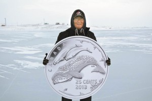 In Cape Dorset, Nunavut, artist Tim Pitsiulak holds a reproduction of the new 25-cent circulation coin he designed for the Royal Canadian Mint, celebrating life in the North. 