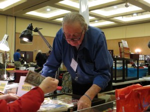 Nick Cowan, owner of the Coin Collector, helping a collector find a banknote.